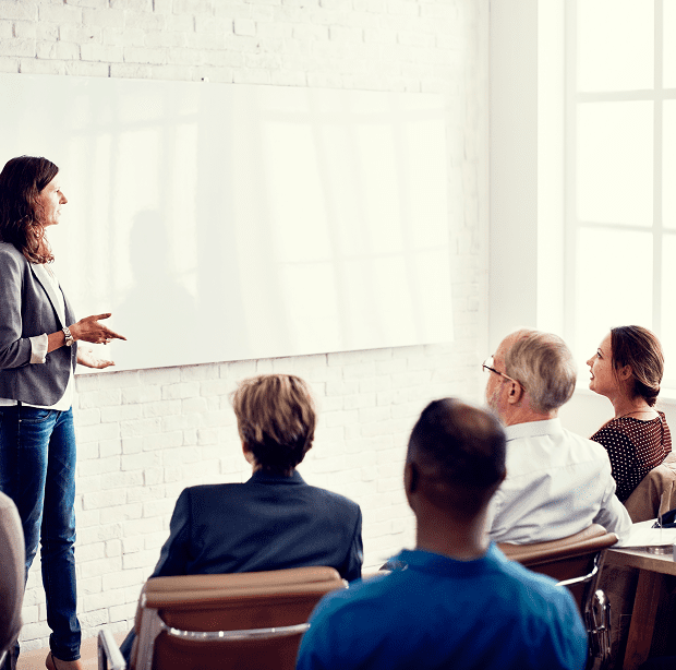 Woman presenting to seated audience in meeting.